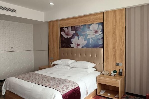 A hotel room with a bed, a nightstand, a telephone, and a small shelf. - Jukai International Hotel (Nan'an)