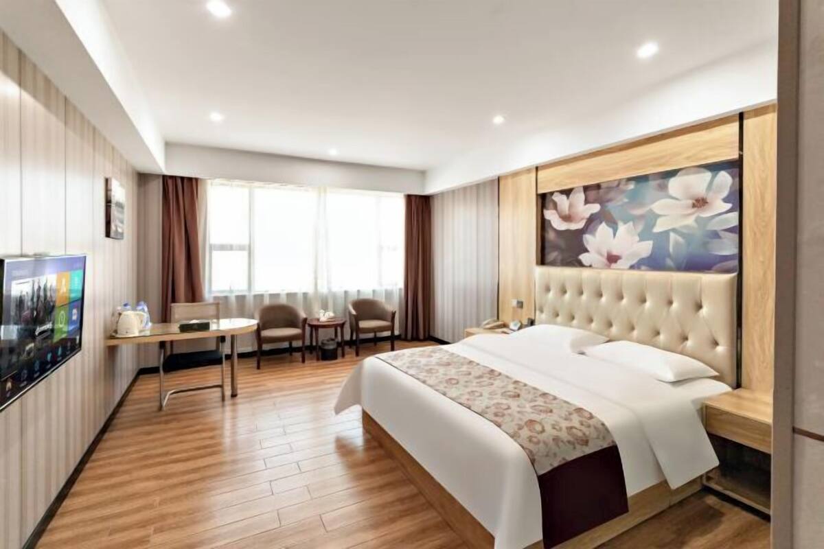 A hotel room with a bed, a TV, a desk, and a chair.