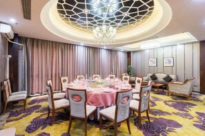 A dining area with a round table set for six, surrounded by chairs with cushioned seats.