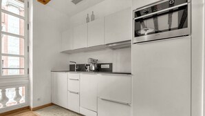 A modern kitchen with white cabinets, a built-in oven, and a coffee maker.