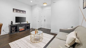 Un salon moderne avec un téléviseur à écran plat, un canapé, une table basse et un tapis à motifs.