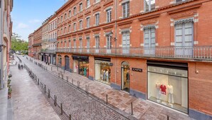 A red brick building with multiple storefronts, including a Zara store. - Frère Jacques - Appt situé plein centre (Toulouse)