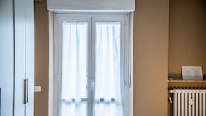 Een kamer met een schuifdeur van glas, een radiator en een plank met een bordje.