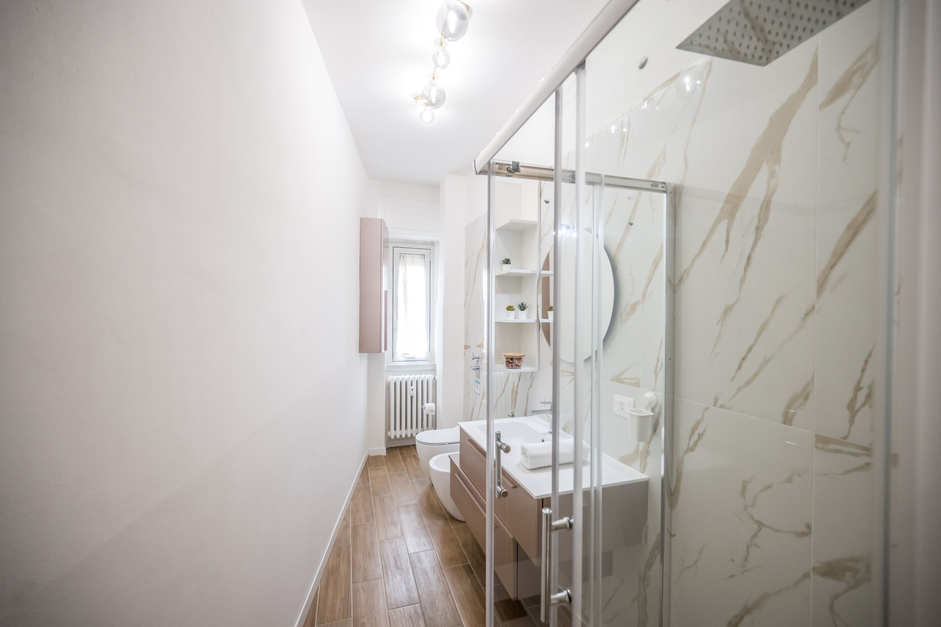 Ein modernes Badezimmer mit einer Glasdusche, einem weißen Waschbecken und einer Toilette.