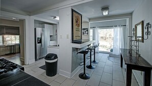 Cocina moderna con refrigerador, estufa y taburetes de bar.