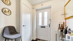 Un couloir avec une chaise, une porte, une table en verre ornée de bougies et des décorations murales.