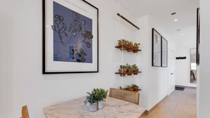 Un interior moderno con una mesa de mármol, plantas en macetas y cuadros en las paredes.
