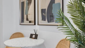 A round table with a speckled white surface, two wicker chairs, and a framed artwork on the wall. - Downtown Montreal Speakeasy 502 | Balcony, Queen Bed, Sofa Bed, Parking & 65` TV (Montreal)