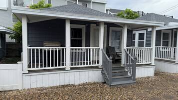 A two-story house with a covered porch, a front staircase, and a small front yard with gravel.