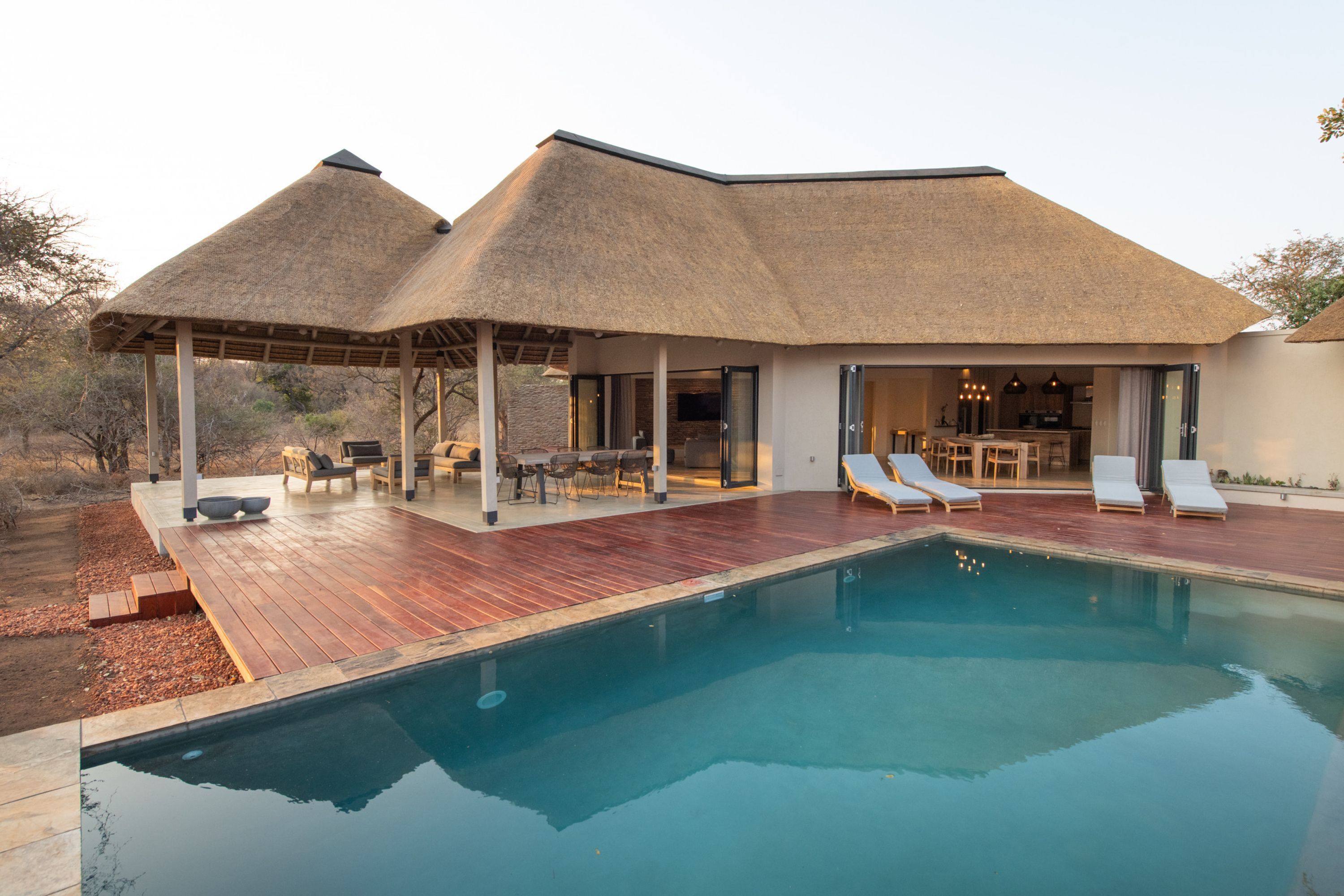 A modern house with a pool, outdoor seating, and a covered patio.
