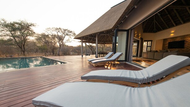 A poolside area with lounge chairs and a covered seating area. - Villa Appelblaar in Hoedspruit (Hoedspruit)