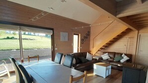 Un vaste espace de vie comprenant une grande table à manger, des canapés en cuir et un escalier.