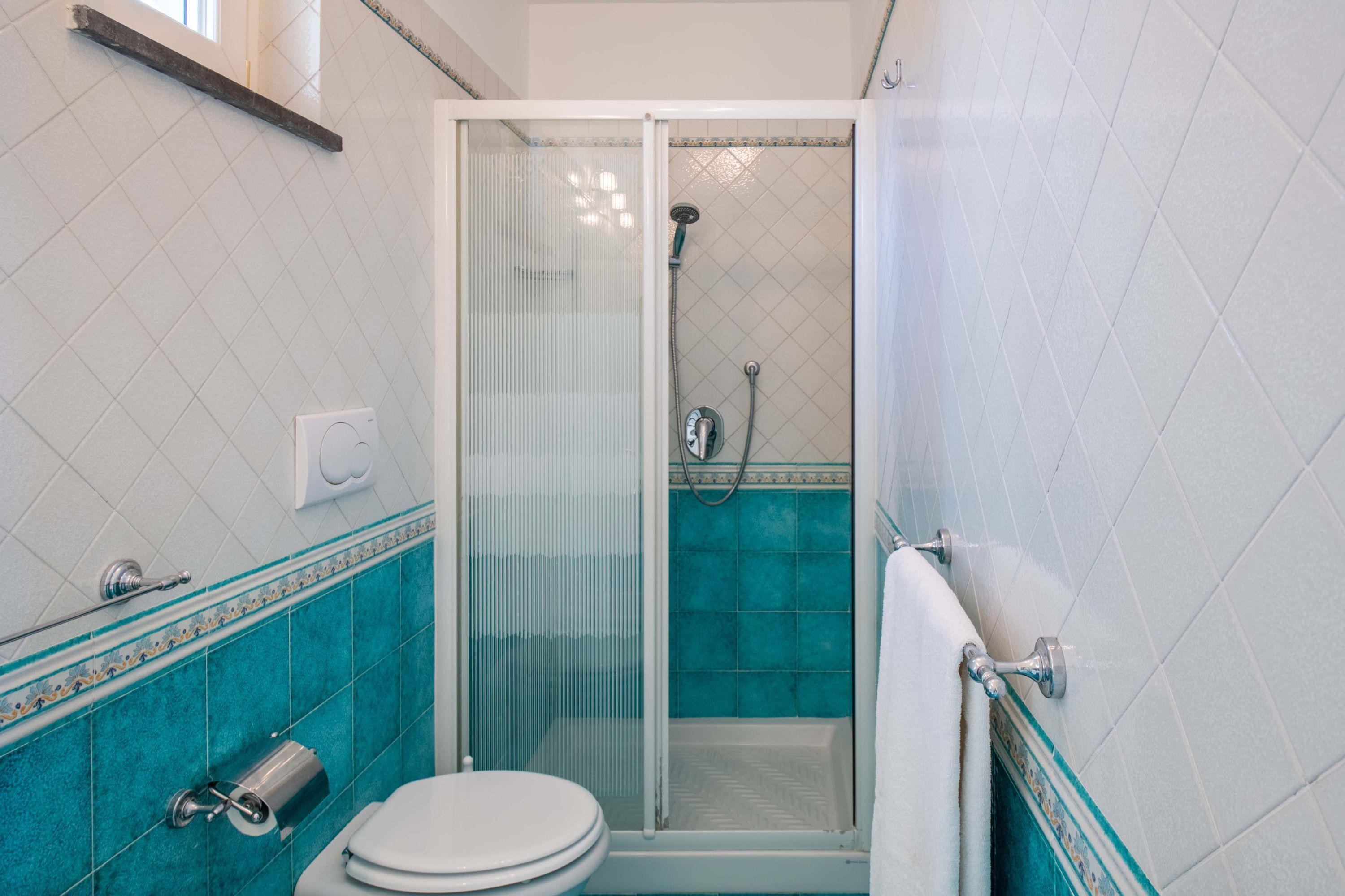 Ein Badezimmer mit Toilette, Duschkabine und Handtuchhalter.