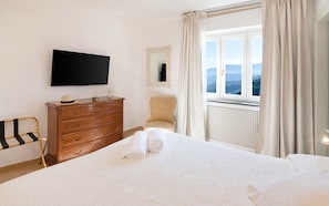 A hotel room with a bed, a dresser, a chair, a television, a window with a view, and a mirror. - Villa Grazielluccia in Sorrento (Sorrento)