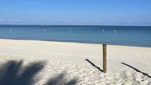 Una playa con arena blanca y un cielo azul despejado.