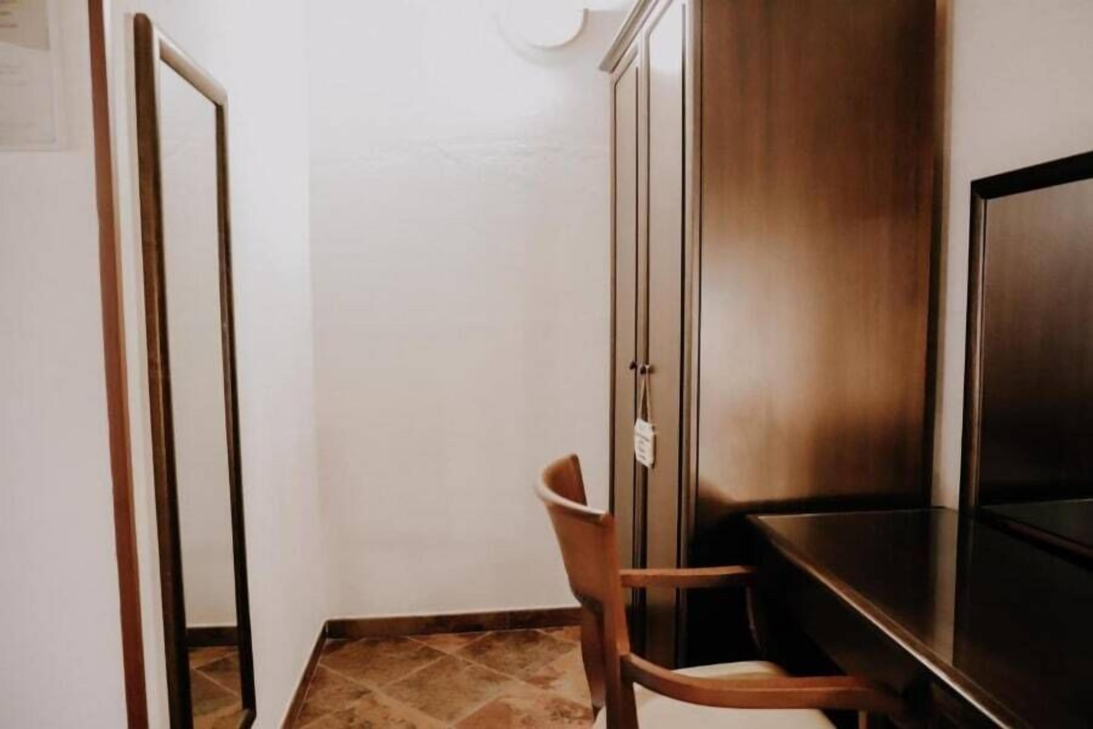 A small, narrow room with a wooden cabinet, a chair, and a television.