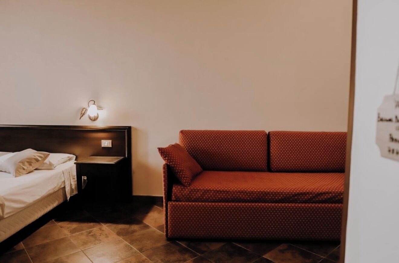 Una camera da letto con un letto, un comodino e un divano rosso.