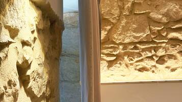 Un baño con pared de piedra, cortina de ducha y un perchero con un pomo amarillo.