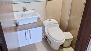 A bathroom with a white sink, a toilet, and a shower stall.