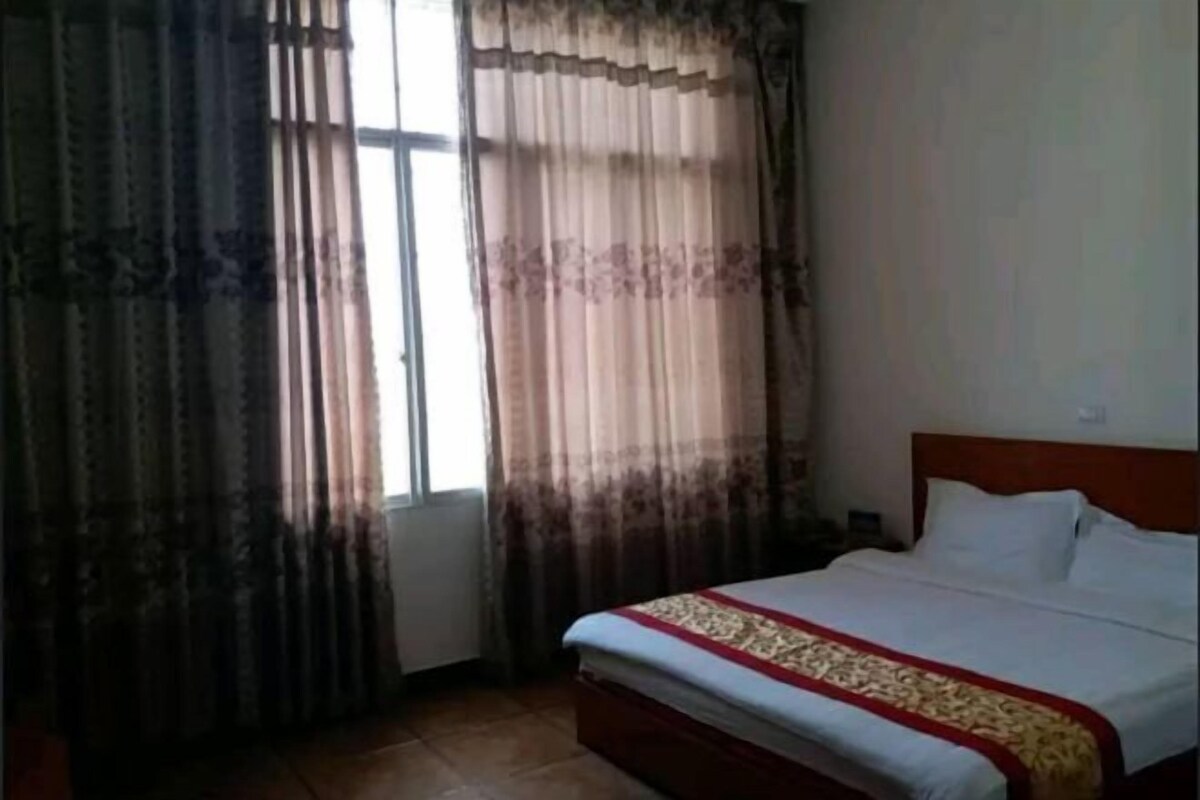 A bedroom with a bed, curtains, and a window.