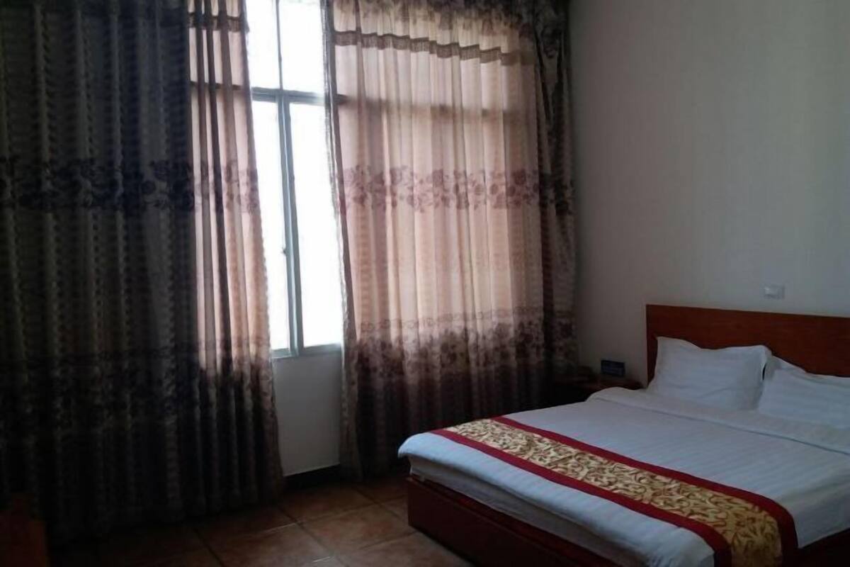 Una habitación de hotel con una cama, cortinas y una ventana.