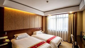 Habitación de hotel con dos camas, un escritorio, una silla, un teléfono y una ventana con cortinas.
