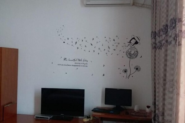 A room with two monitors on a desk, a wall decal with a girl and birds, and a window with curtains. - Quanzhou Longshi Hotel (Quanzhou)