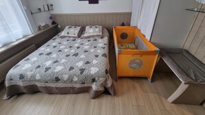 A bedroom with a bed, a nightstand, a dresser, and a wall-mounted artwork.