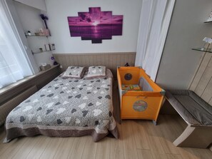A bedroom with a bed, a nightstand, a dresser, and a wall-mounted artwork.