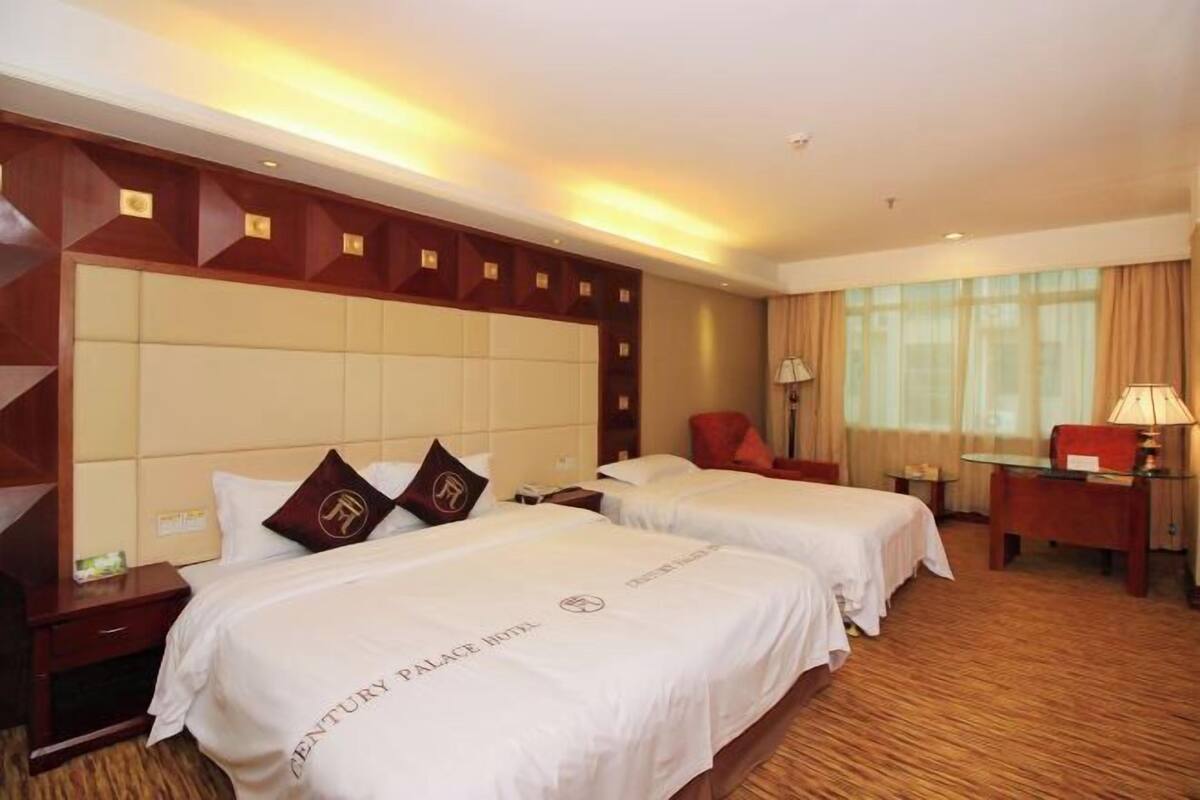 Una habitación de hotel con dos camas, cabecero de madera, un escritorio y una silla.