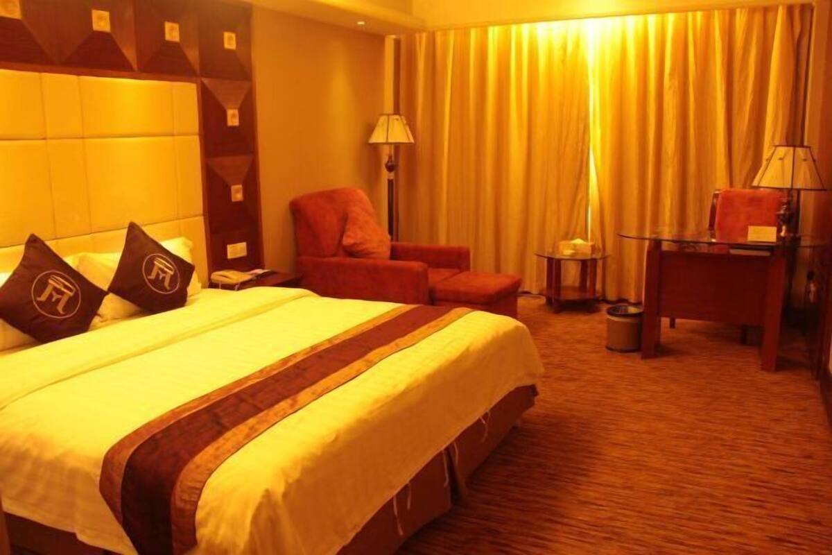 Una habitación de hotel con una cama grande, una silla, un escritorio y una lámpara.