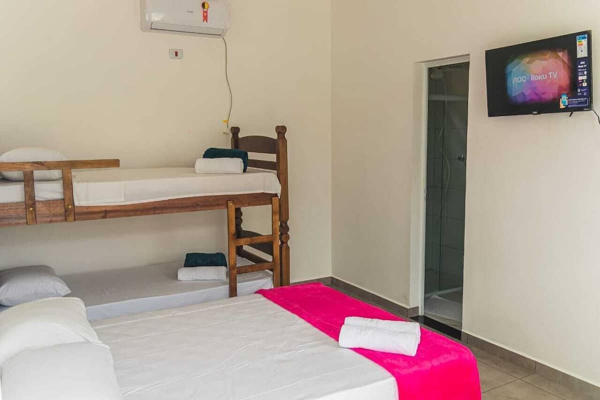 Una habitación con literas, una cama plana, televisión y zona de ducha.