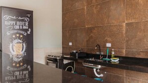 Una cocina moderna con encimera negra, electrodomésticos de acero inoxidable y salpicadero de azulejos.