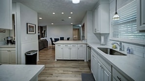 A modern kitchen with white cabinetry, a central island, and a built-in sink.