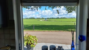 A kitchen window with a view of a green field and a blue sky. - De Mast bij Fort Vechten,house in old farmhouse, on the countryside near Utrecht (Bunnik)