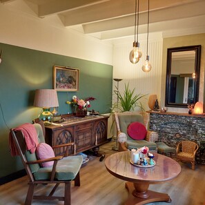 A cozy living room with a round coffee table, a green wall, a fireplace, and a large mirror. - De Mast bij Fort Vechten,house in old farmhouse, on the countryside near Utrecht (Bunnik)