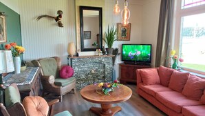 A living room with a stone fireplace, a television, and various decorative items. - De Mast bij Fort Vechten,house in old farmhouse, on the countryside near Utrecht (Bunnik)