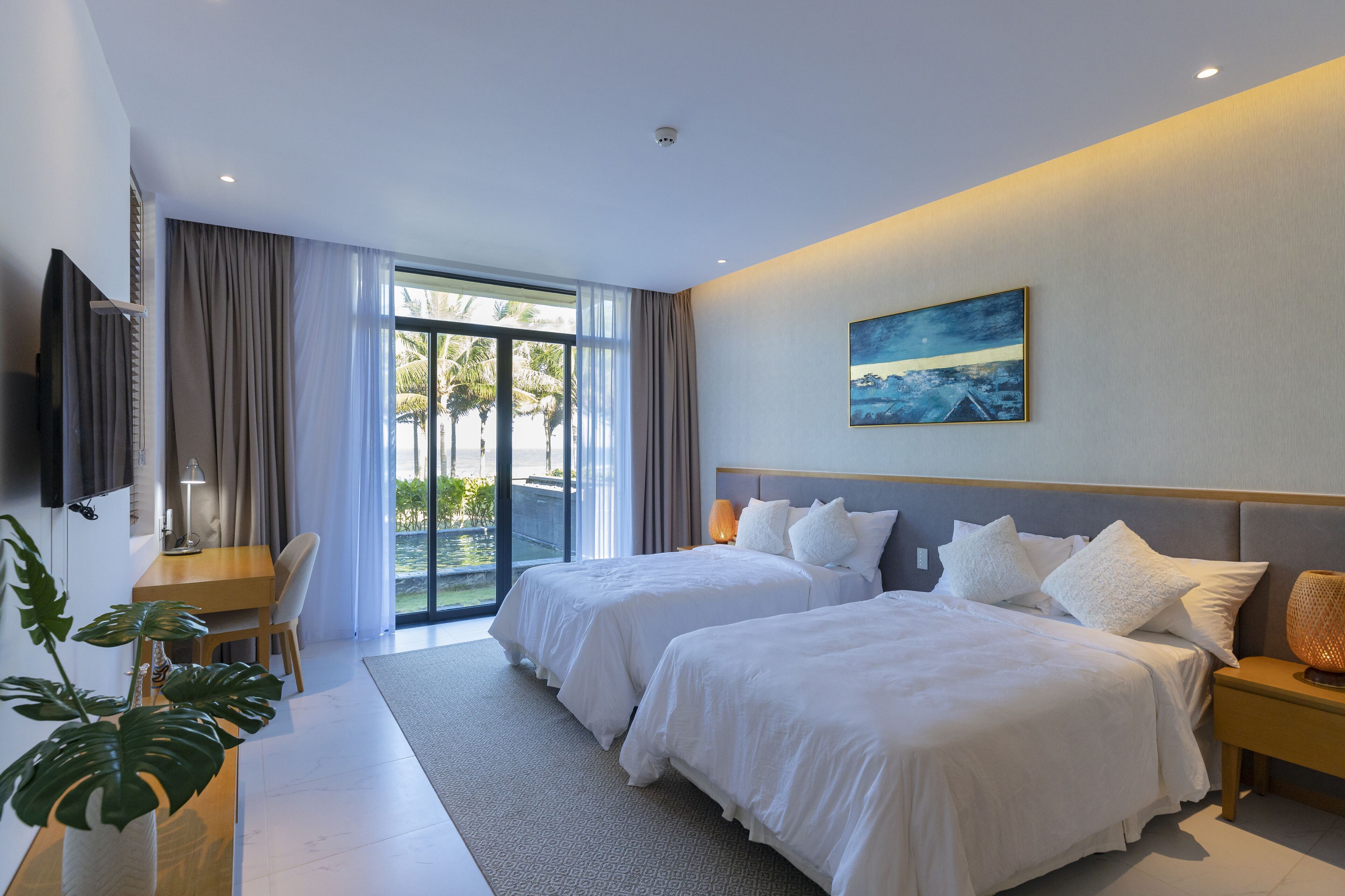 A modern hotel room with two beds, a desk, a TV, and a large window with curtains.