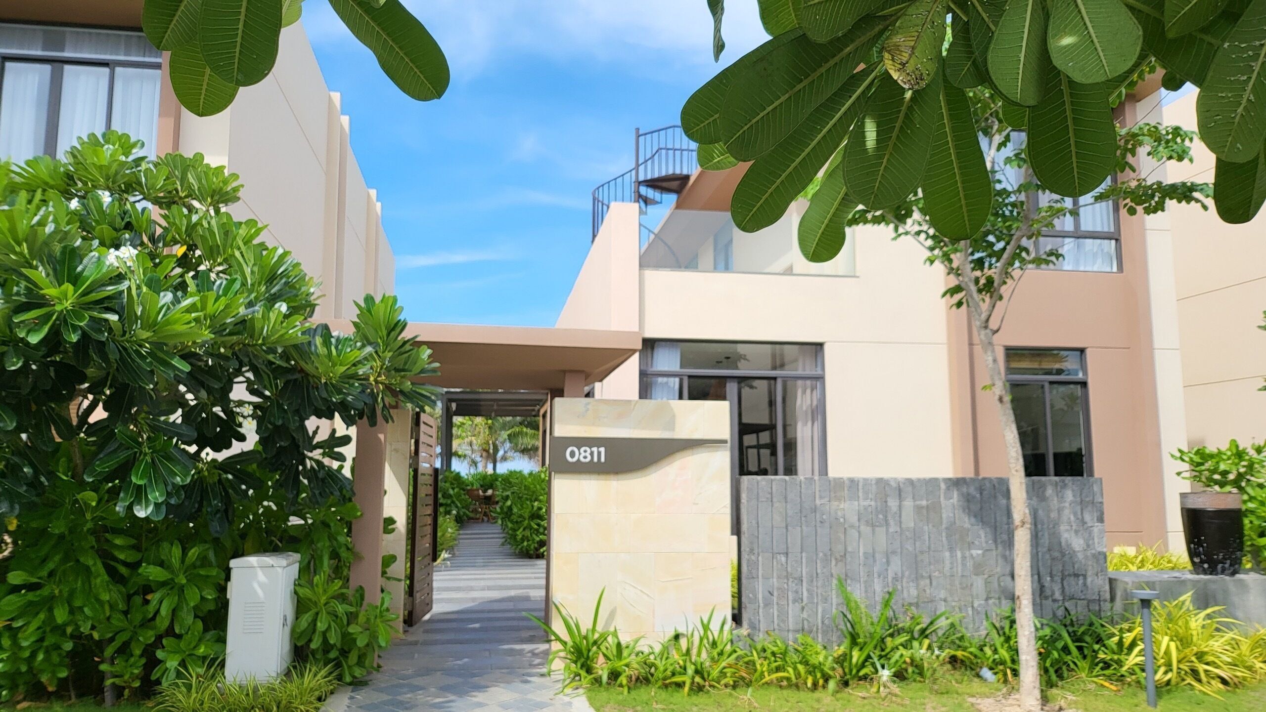 A modern residential building with a paved pathway leading to the entrance.