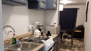 A kitchen with a stove, sink, and cabinets. There is a dining area with a table and chairs. - Casa Raquelina (Ensenada)