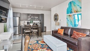 A modern living room with a brown leather sofa, a colorful rug, and a dining area with a kitchen in the background. - Beautiful 1-Bedroom Apartment@Walk to Uptown@Fast WiFi@In-Unit W/D (Minneapolis)