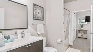 A modern bathroom with a large mirror, a sink with toiletries, a toilet, and a shower area. - Beautiful 1-Bedroom Apartment@Walk to Uptown@Fast WiFi@In-Unit W/D (Minneapolis)