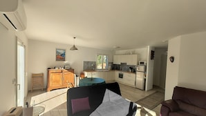 A spacious living area with a sofa, a dining table, and a kitchen in the background. - Maison de Vacances Plain Pied 6 Couchages -2 sdb - Jardin -vernet les Bains (Vernet-les-Bains)