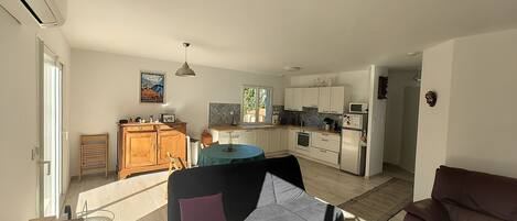 Amplia sala de estar con sofá, una mesa de comedor y una cocina al fondo.