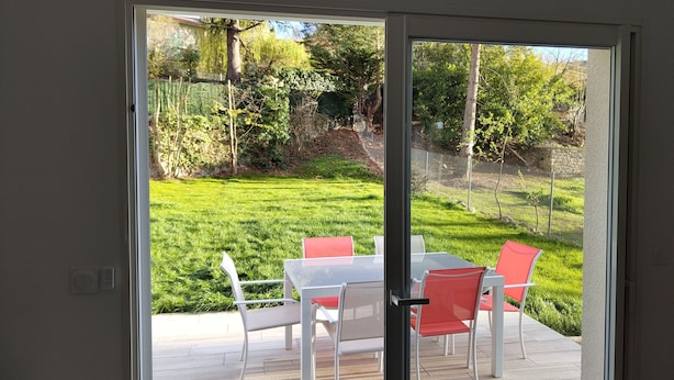 A sliding glass door leading to an outdoor patio with a table and chairs. - Maison de Vacances Plain Pied 6 Couchages -2 sdb - Jardin -vernet les Bains (Vernet-les-Bains)