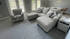 A living room with a grey sectional sofa, a patterned armchair, and a small side table.