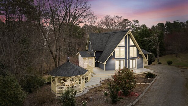 A two-story house with a covered porch and a small gazebo.