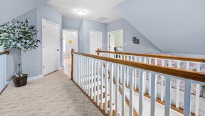 A hallway with a staircase leading to a bedroom.