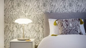 Una cama bien hecha con un cojín estampado de cebra y una lámpara en una mesita de noche.