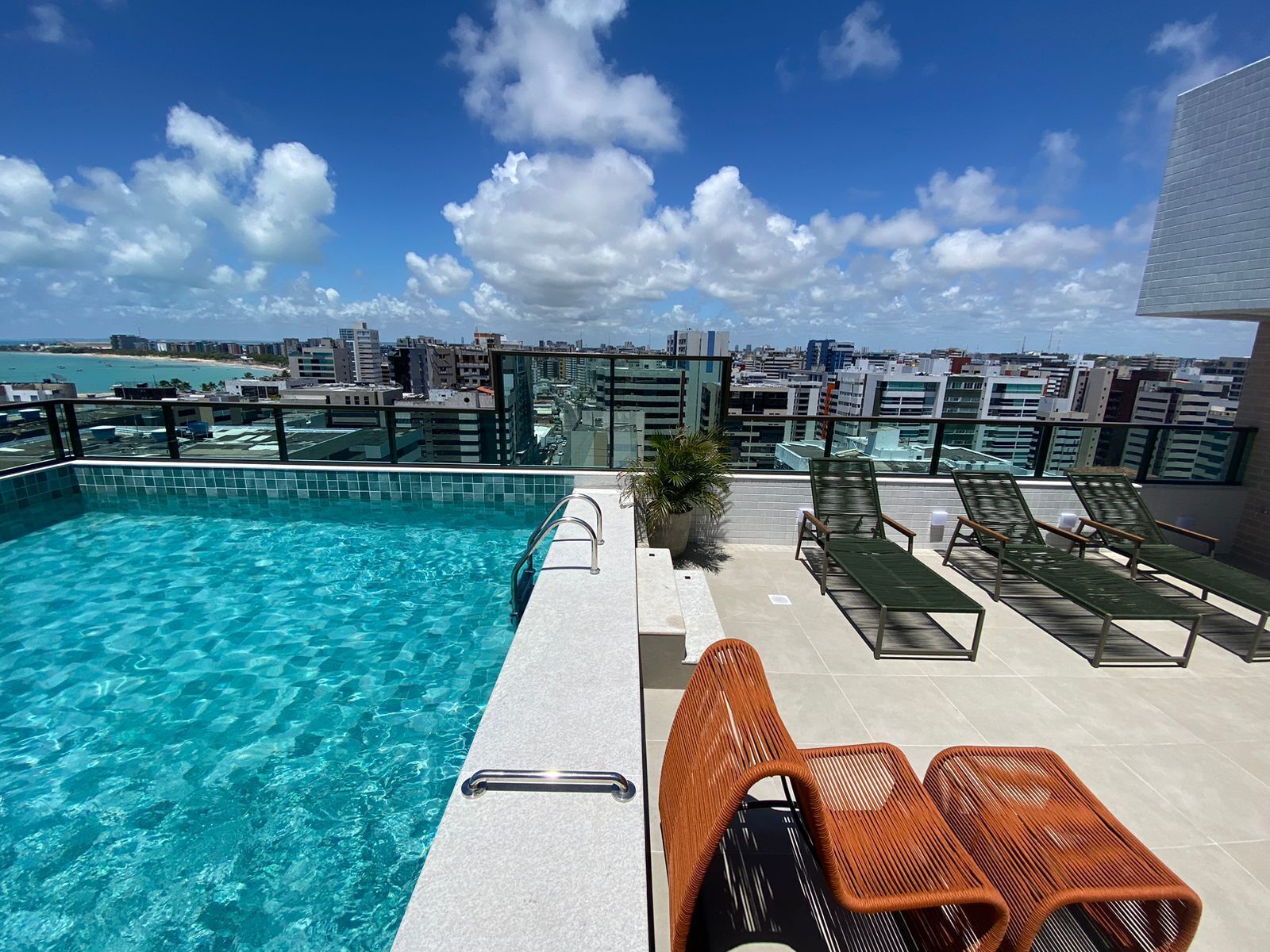 Une piscine sur le toit, avec une eau d’un bleu cristallin, entourée de chaises longues et offrant une vue sur la ville.
